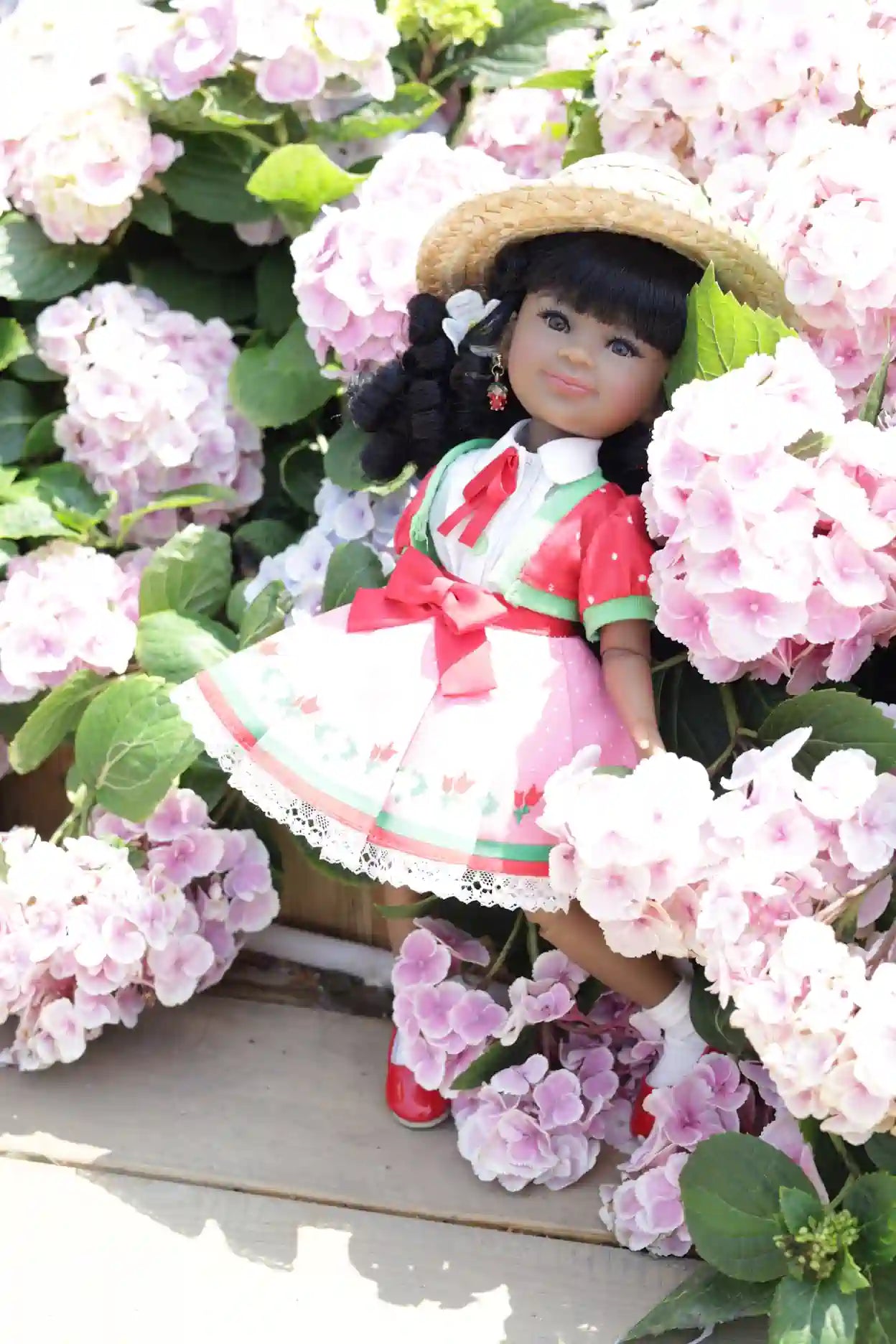 Kyra in a floral setting with pink flowers and green leaves