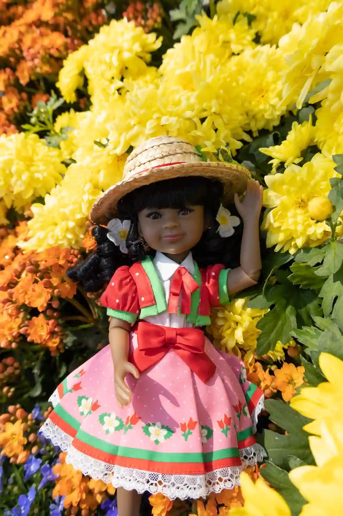 Kyra in a colorful dress and hat surrounded by flowers