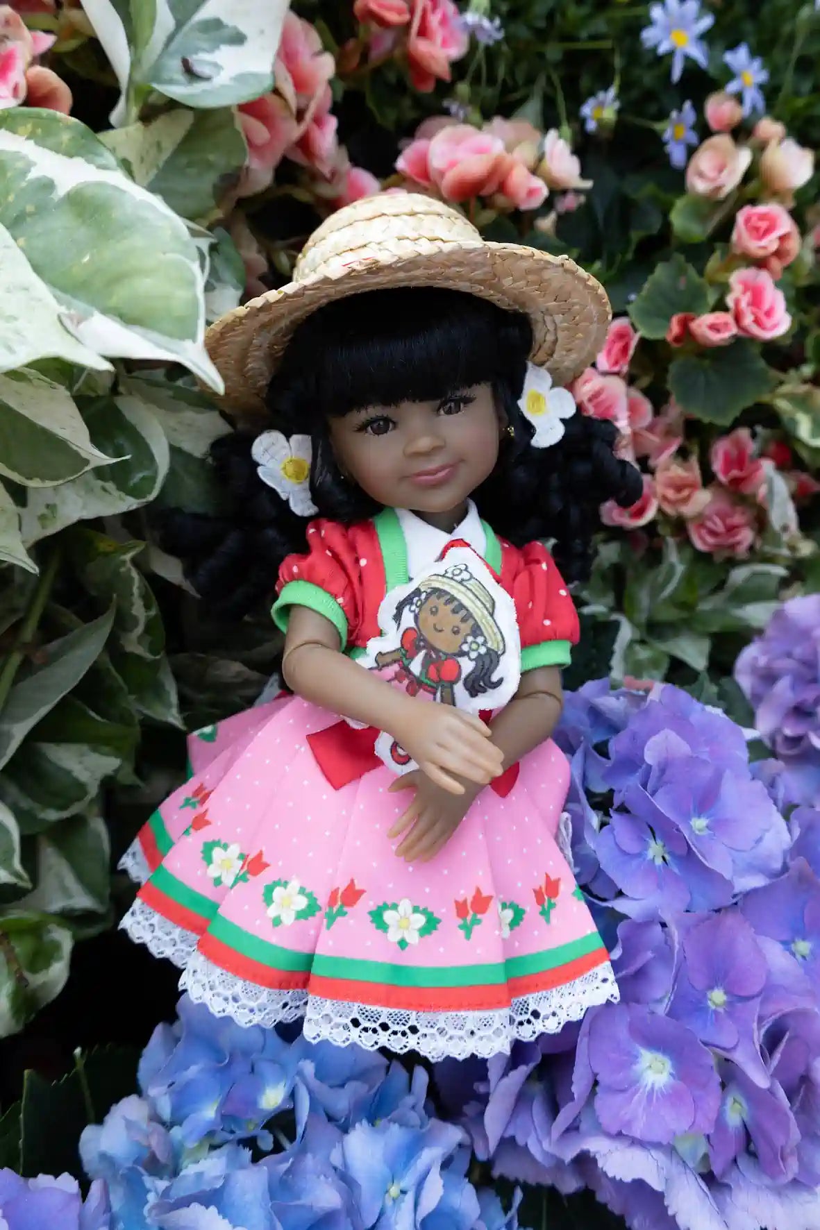 Kyra in pink outfit with floral hat and dress, surrounded by flowers