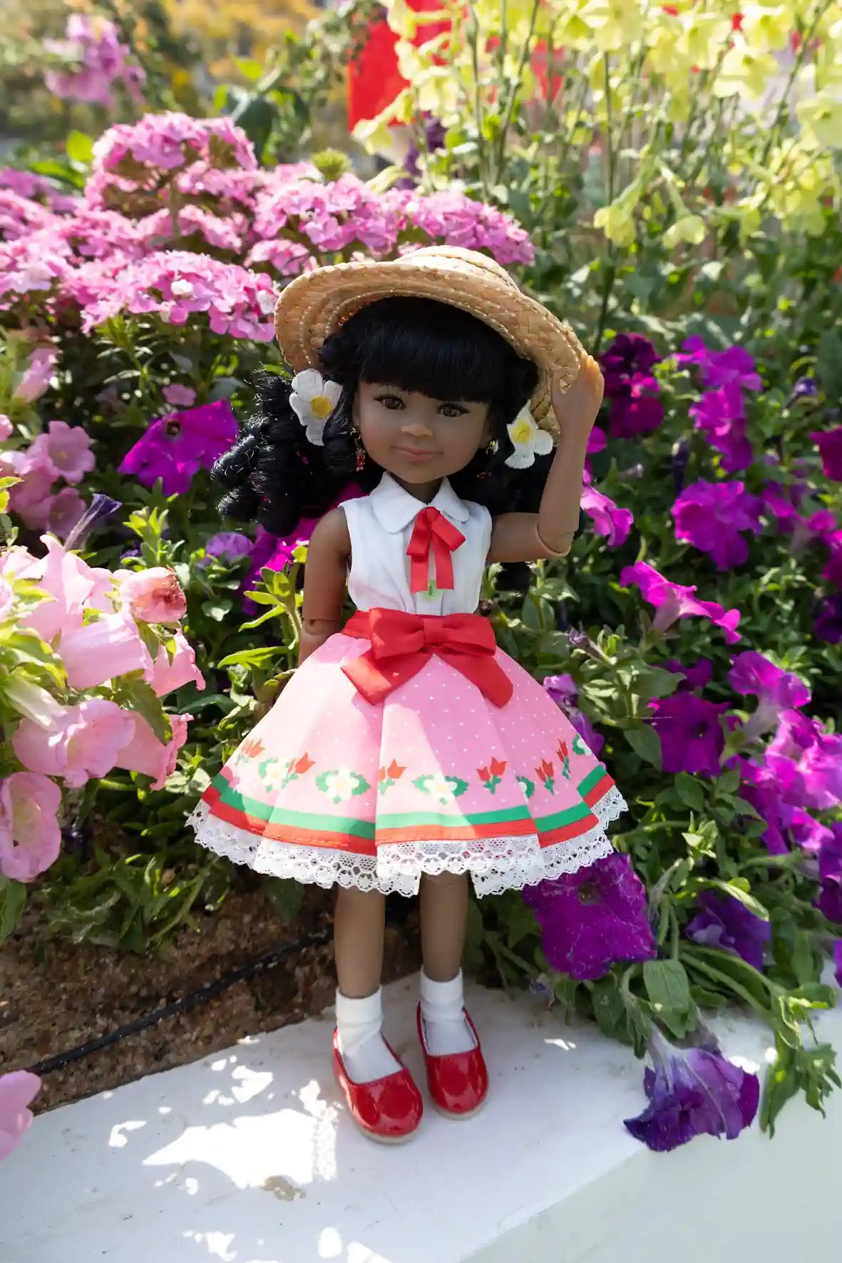 Kyra in a traditional outfit with a straw hat, standing among flowers