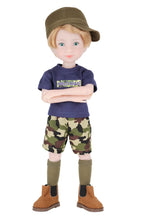 Rory wearing a blue shirt text, camouflage shorts, and brown boots on a white background