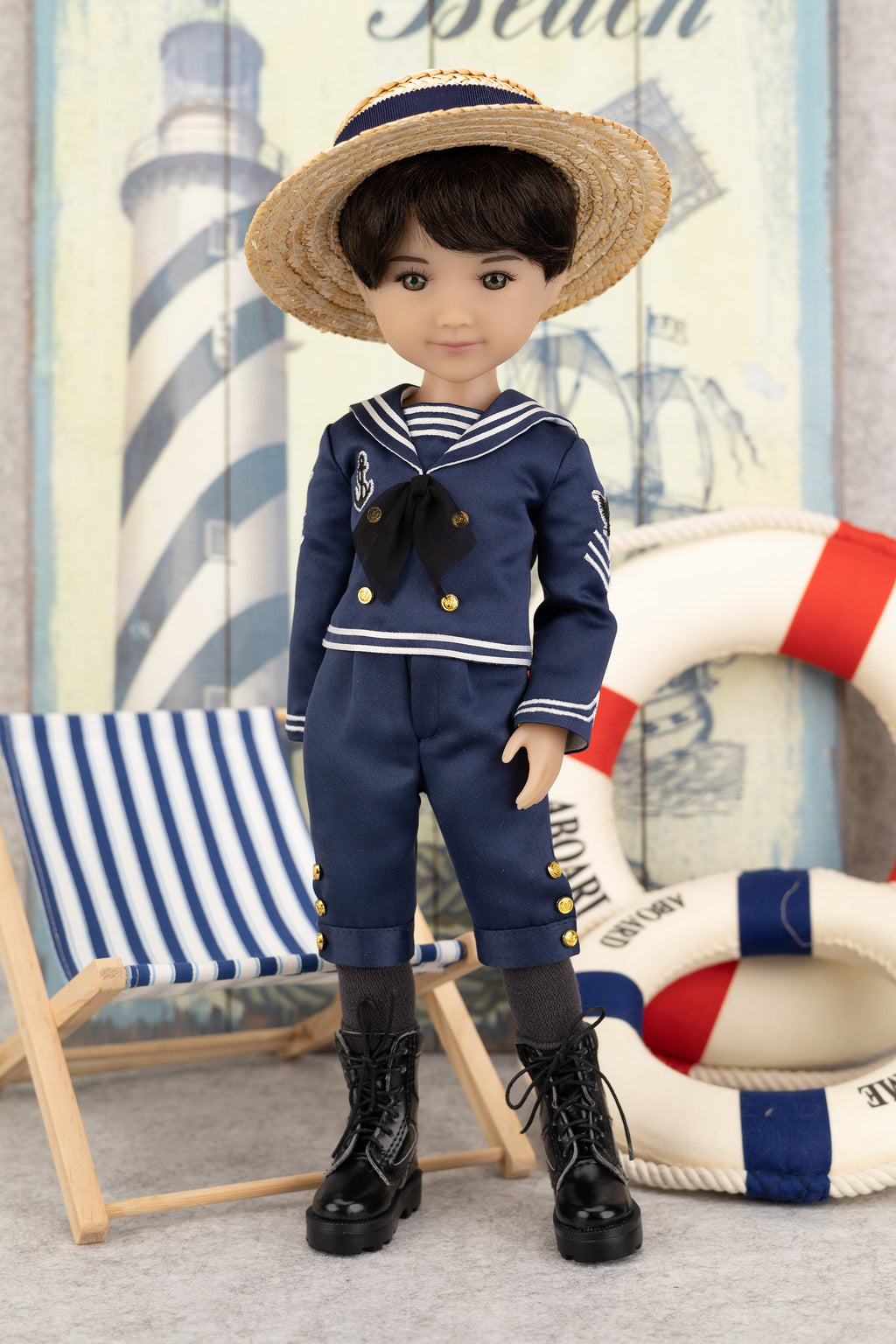 Tyler in a navy blue sailor outfit with a straw hat, standing next to a striped chair and life buoy.