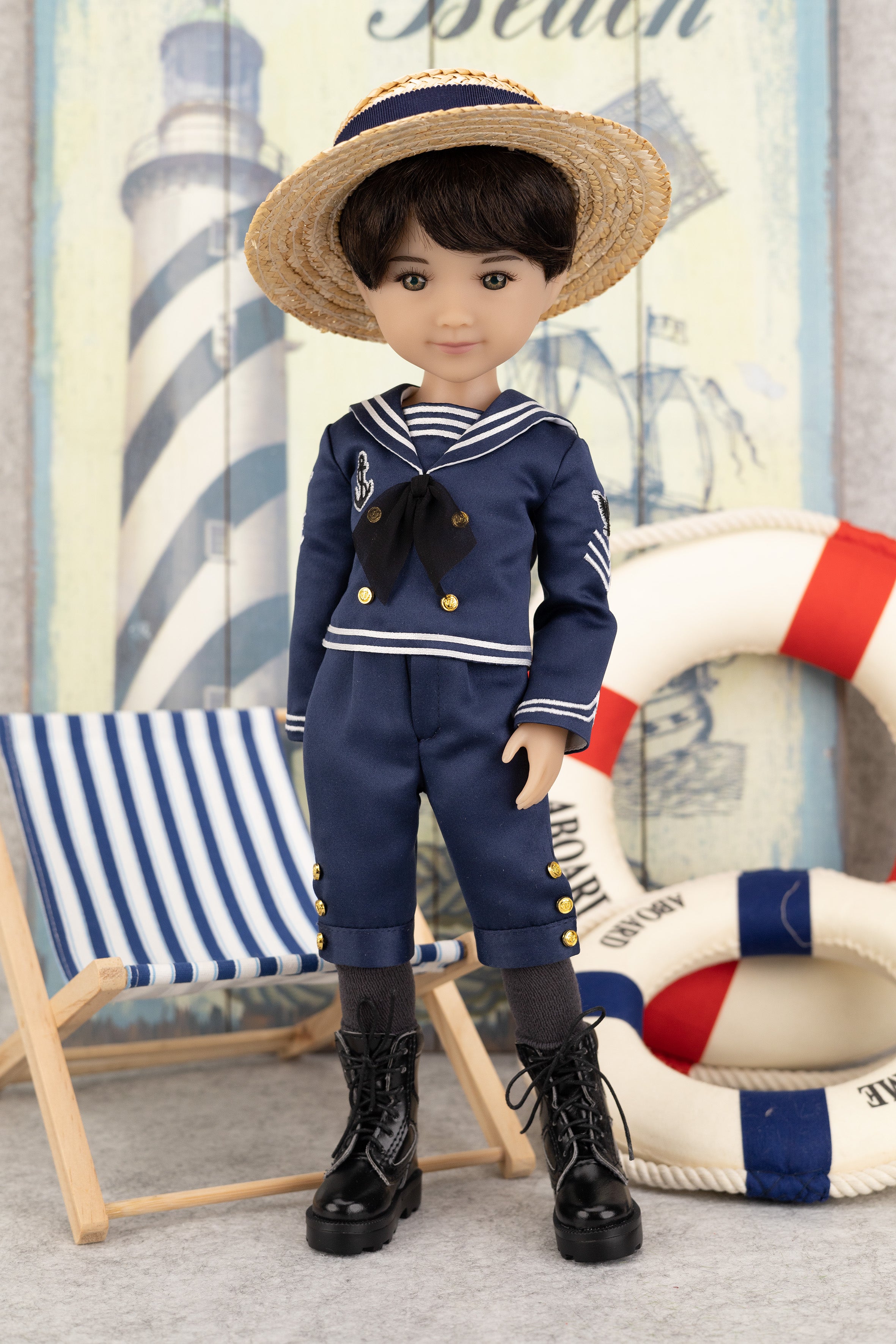 Tyler in a navy blue sailor outfit with a straw hat, standing next to a striped chair and life buoy.