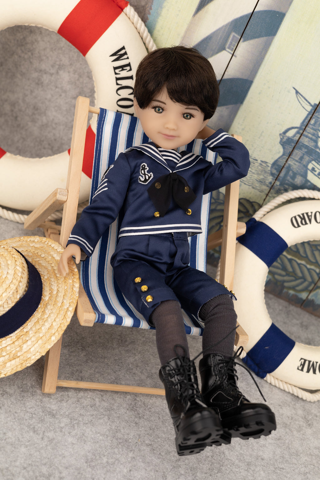 Tyler in a navy outfit sitting on a striped chair with nautical-themed background
