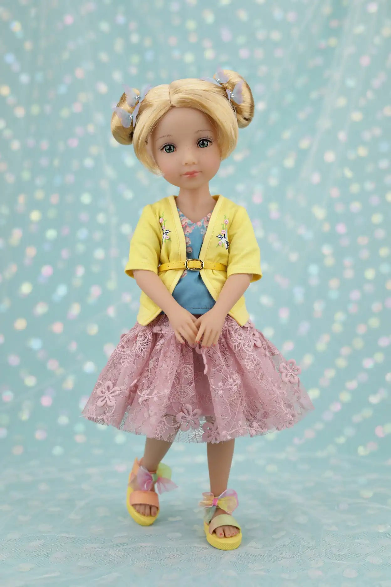 Juniper wearing a yellow cardigan, pink skirt, and sandals on a light blue background