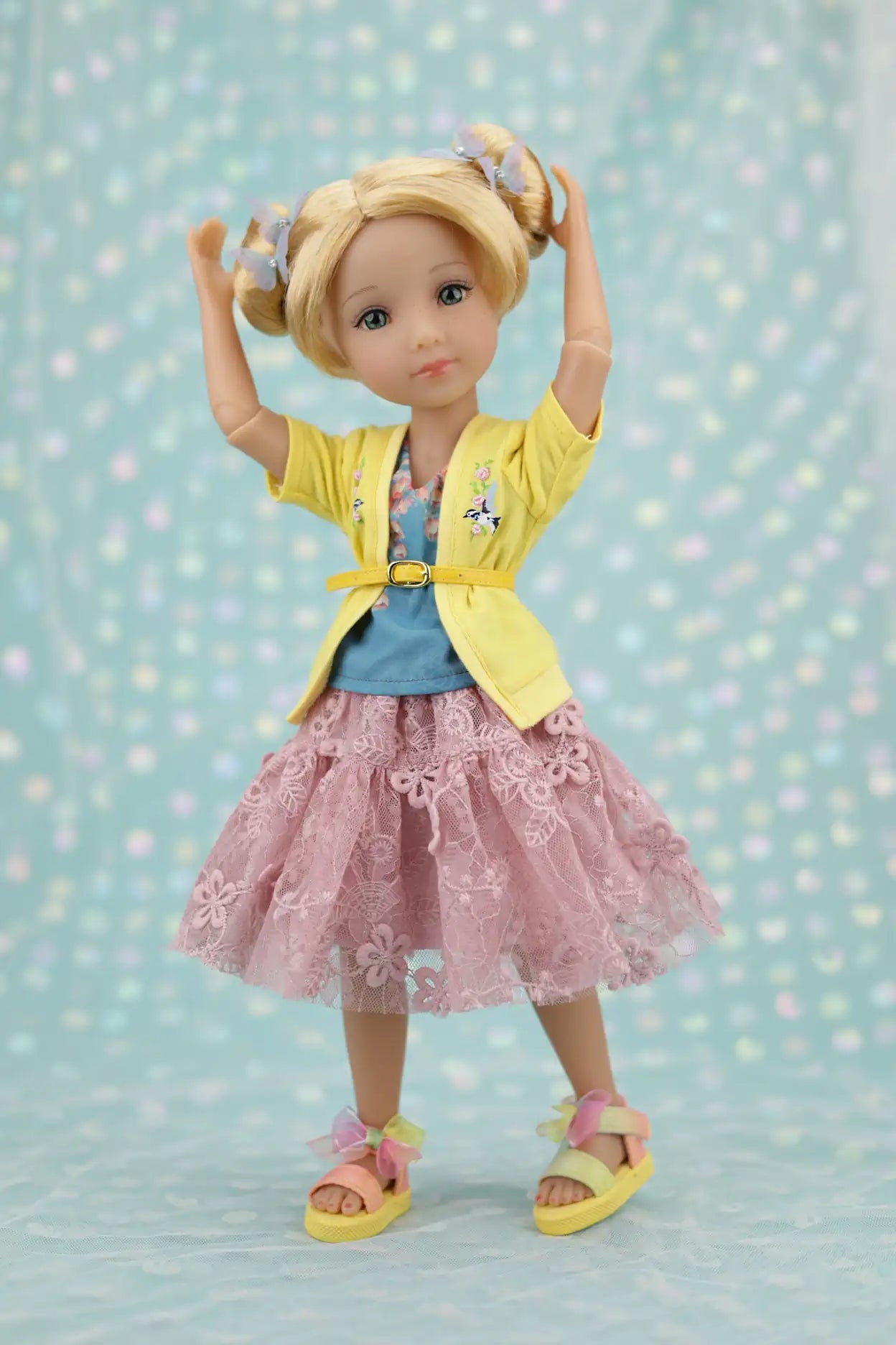 Juniper wearing a yellow jacket, blue shirt, and pink skirt against a light blue polka dot background