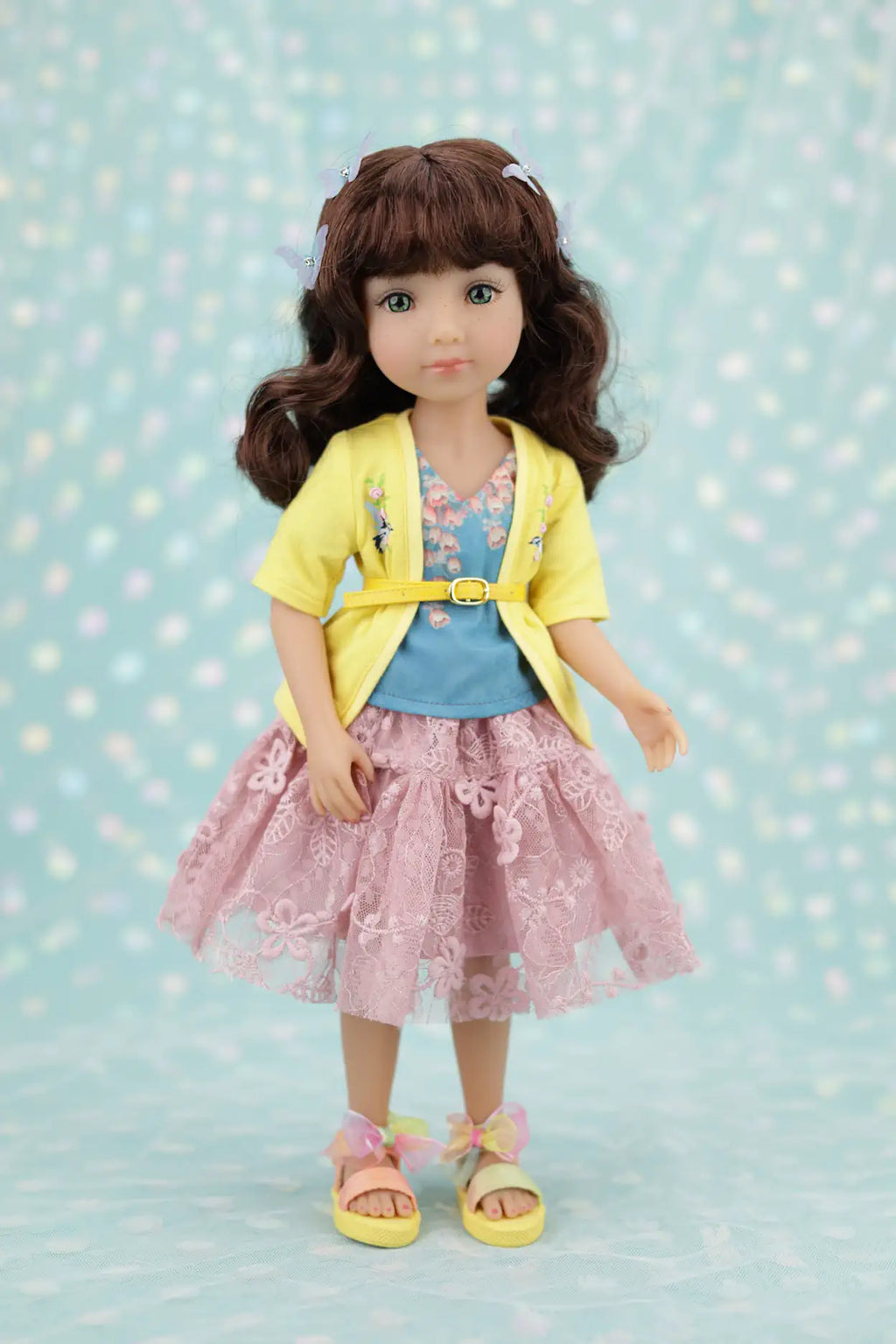 Juniper wearing a yellow jacket, blue shirt, and pink skirt against a light blue background with white dots.