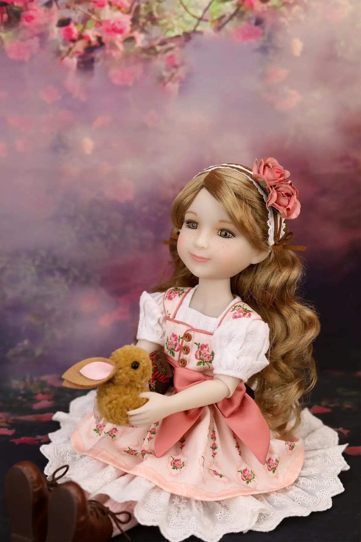 Eden in a floral dress holding a teddy bear with a soft, blurred background