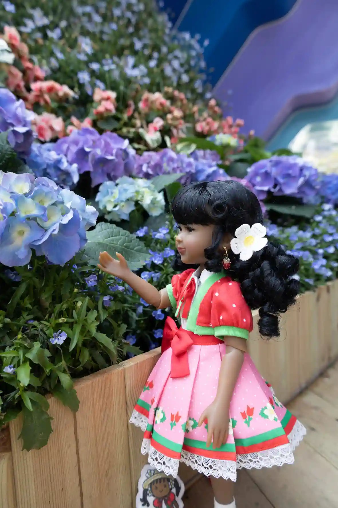 Kyra in a pink dress with a flower in hair standing among flowers