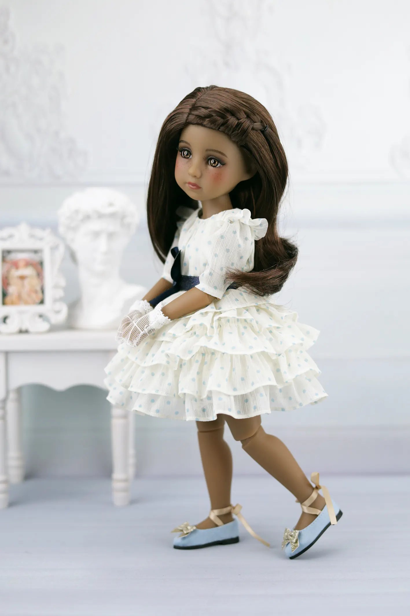 Ruth wearing a white dress with ruffles in a minimalistic setting
