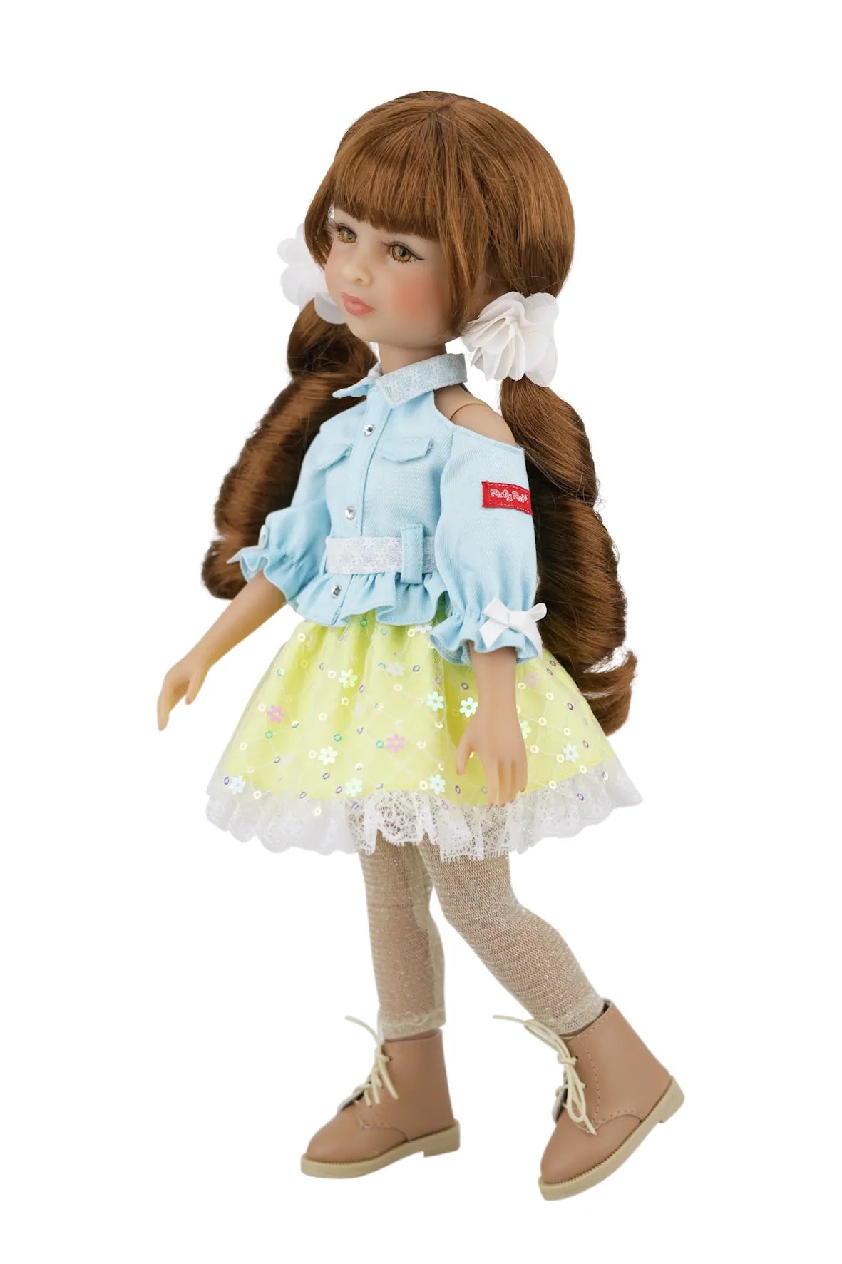 Valeria with long brown hair styled in pigtails, wearing a light blue shirt, yellow dress with white lace, beige leggings, and brown shoes on a white background.