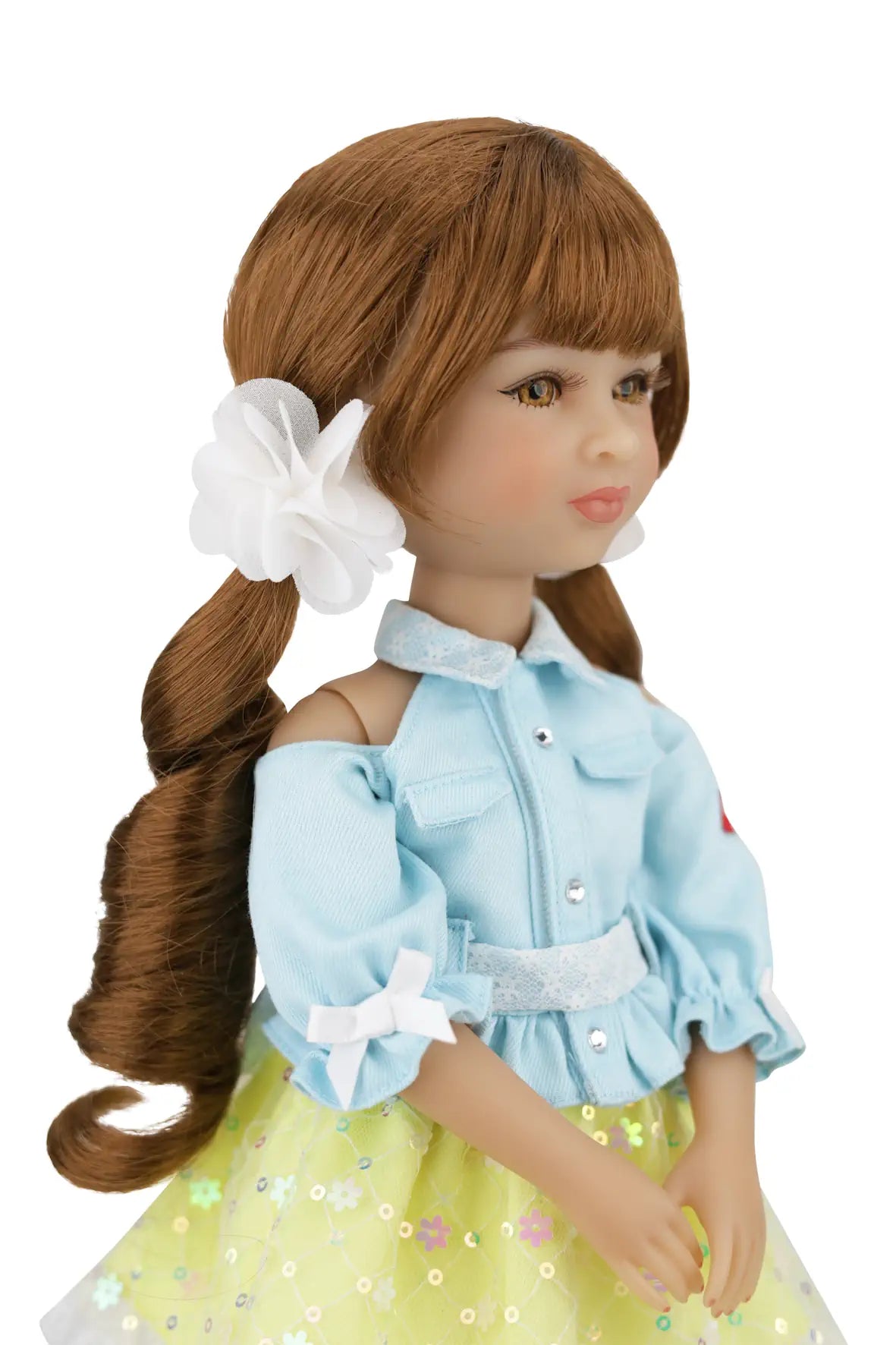 Valeria with brown hair, wearing a light blue top and yellow skirt with a white flower accessory.