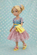 Juniper wearing a floral dress with a yellow apron against a polka dot background