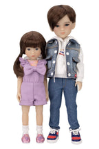 Two dolls, one girl and one boy, wearing outfits with a denim jacket and purple dress.