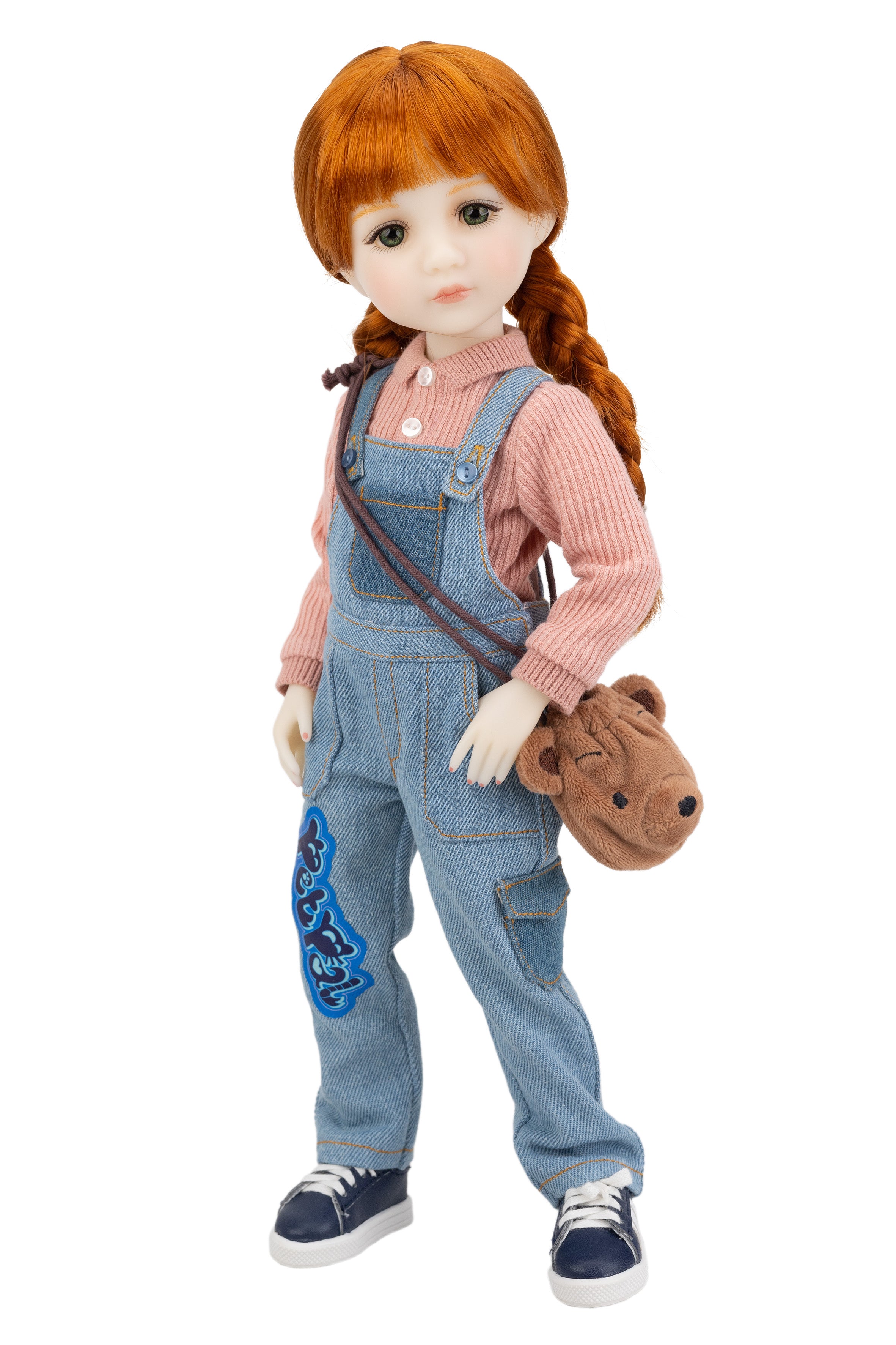 Doll with red hair in pigtails, wearing a pink shirt and blue denim overalls, holding a brown teddy bear.