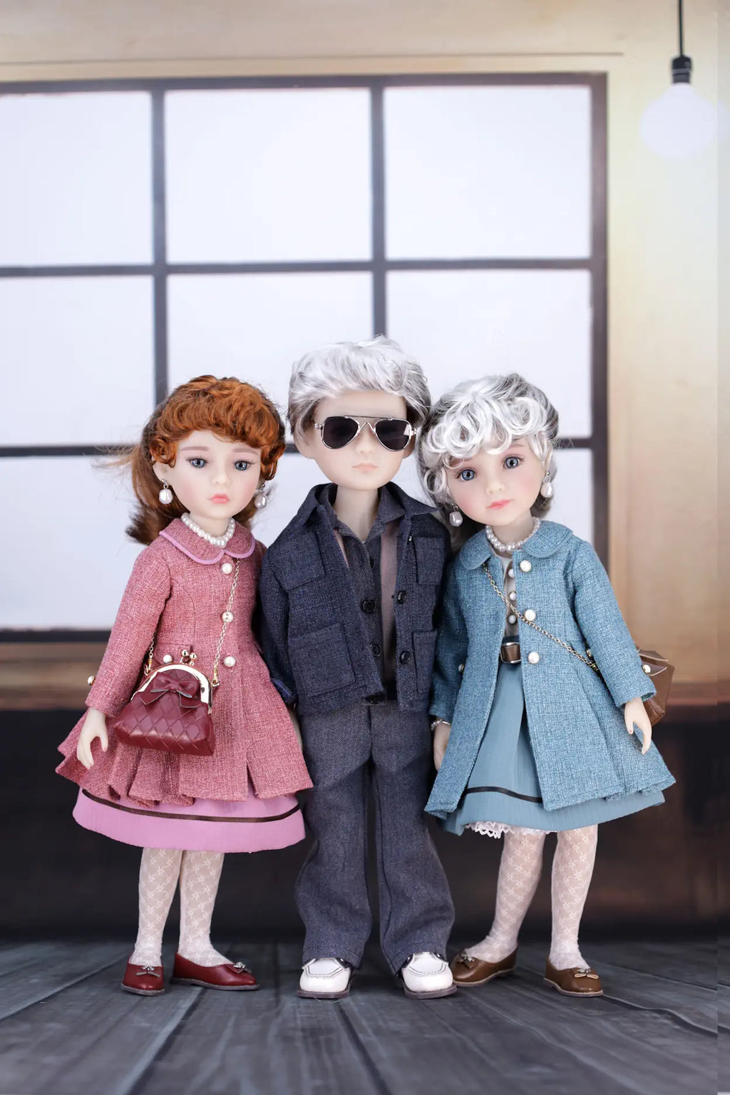 Three dolls in stylish outfits standing together indoors.