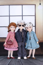 Three dolls in stylish outfits standing together indoors.