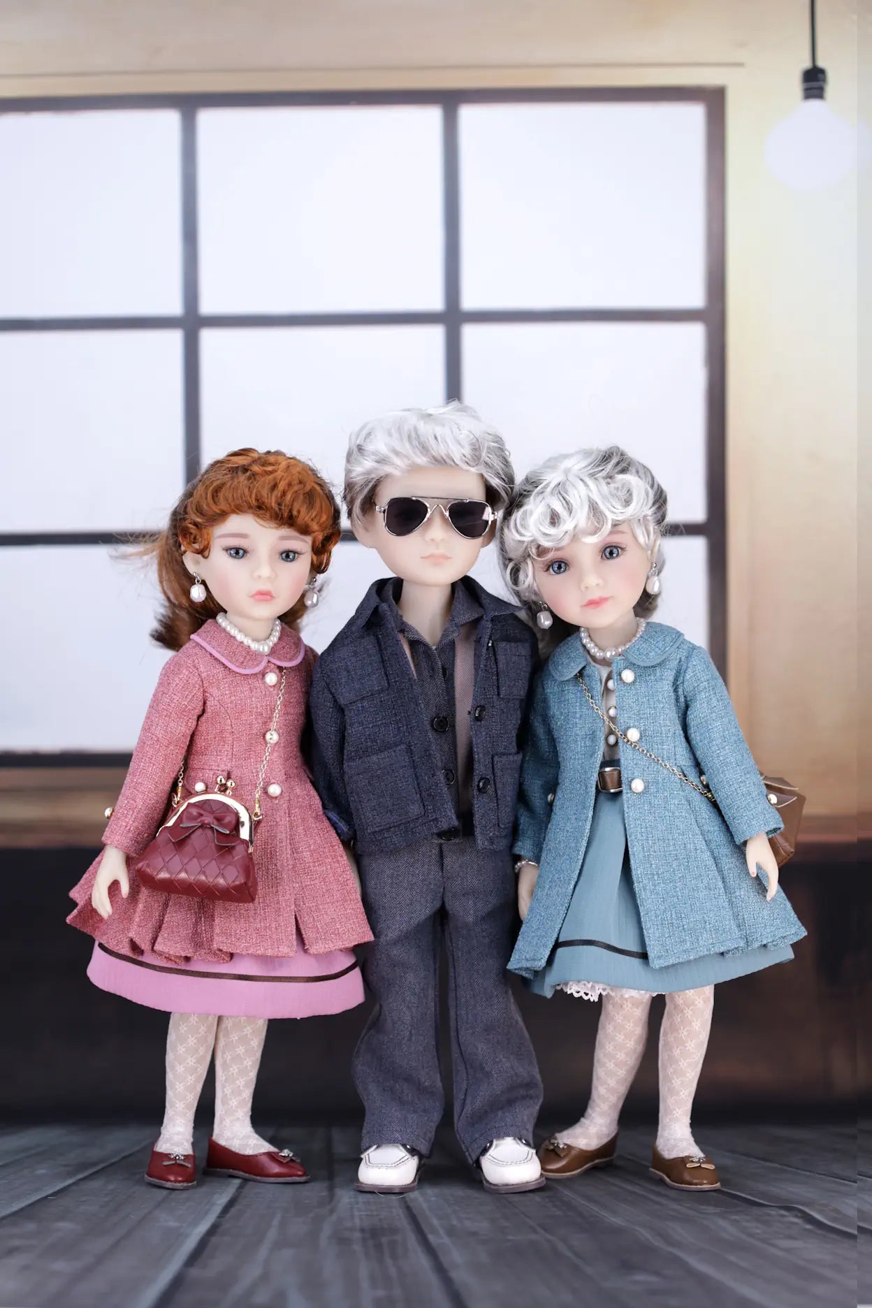 Three dolls in stylish outfits standing together indoors.