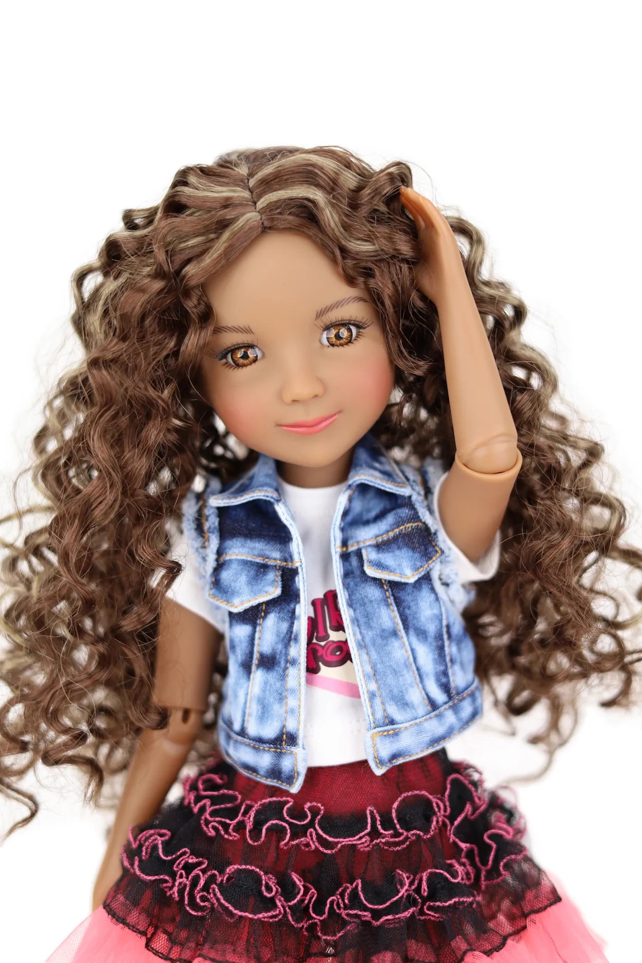 Doll with curly hair wearing a denim jacket and pink skirt on a white background