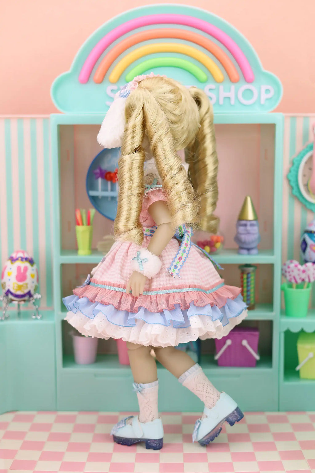 Doll in a colorful room with shelves and a rainbow arch.