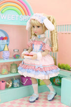 Doll in a pastel-themed room with rainbow and 'Sweet Shop' sign