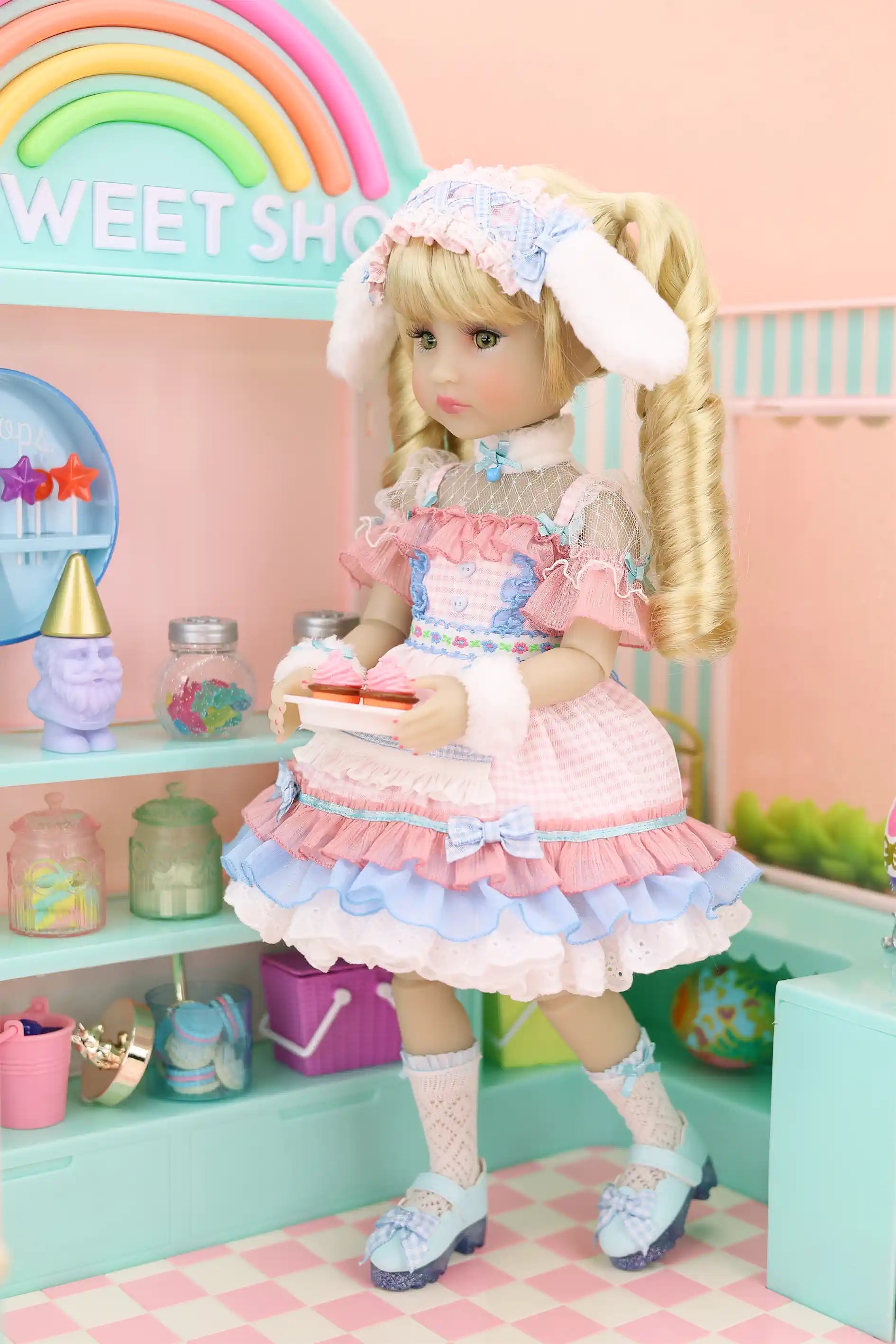 Doll in a pastel-themed room with rainbow and 'Sweet Shop' sign