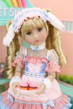 Doll with blonde hair and a pink outfit holding a small cake in a colorful room.