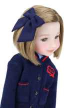 Doll wearing a navy blue outfit with a large bow in hair on a white background