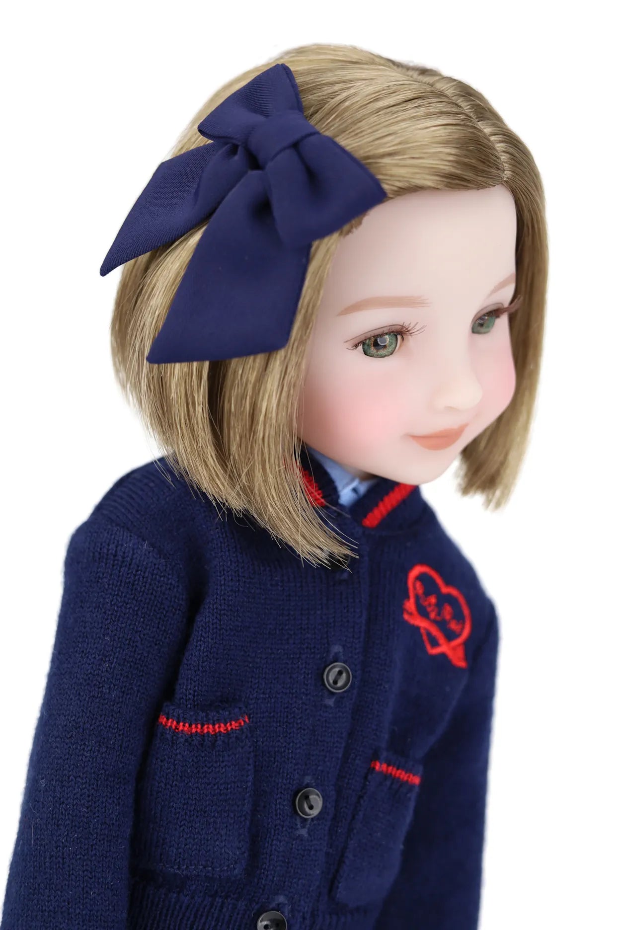 Doll wearing a navy blue outfit with a large bow in hair on a white background