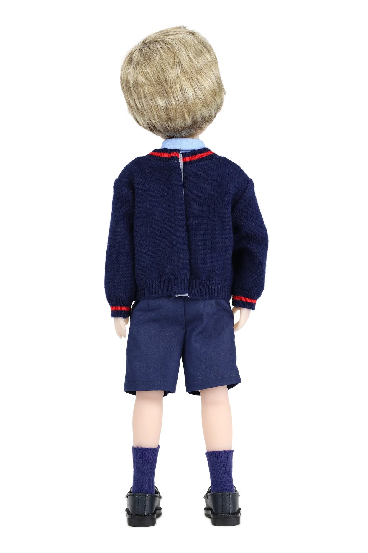 Back view of a doll wearing a navy sweater and shorts set on a white background