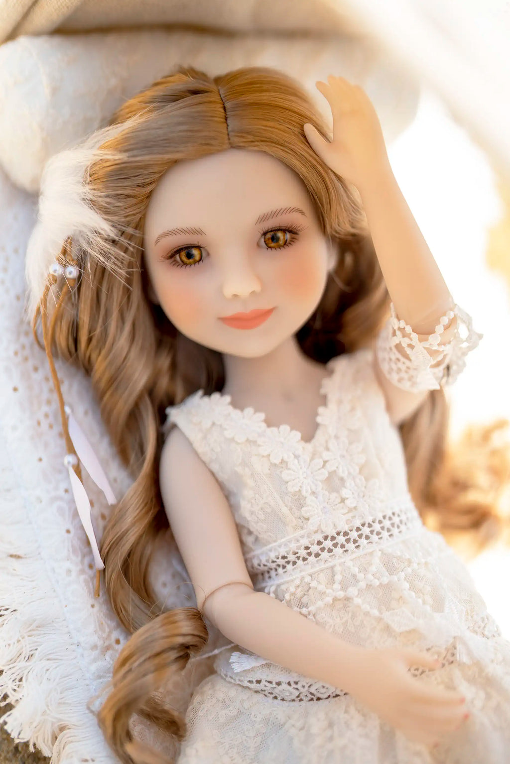 Doll with long brown hair wearing a white lace dress against a blurred background