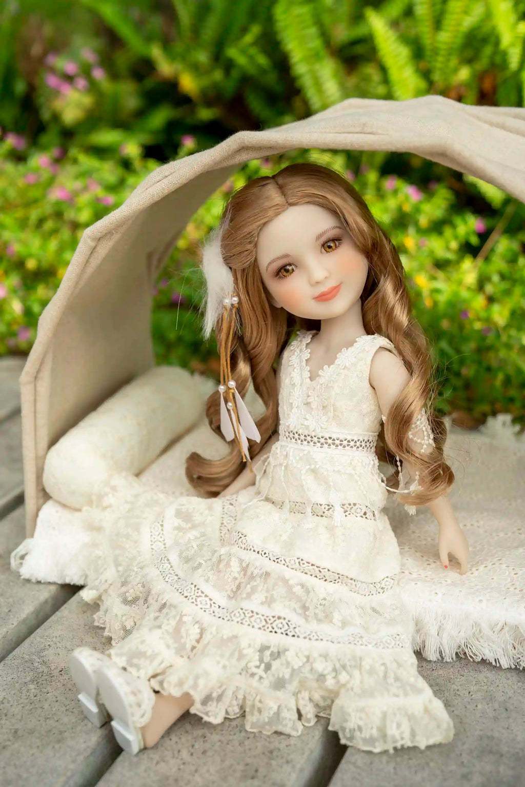 Doll in a white dress sitting under a canopy with greenery in the background