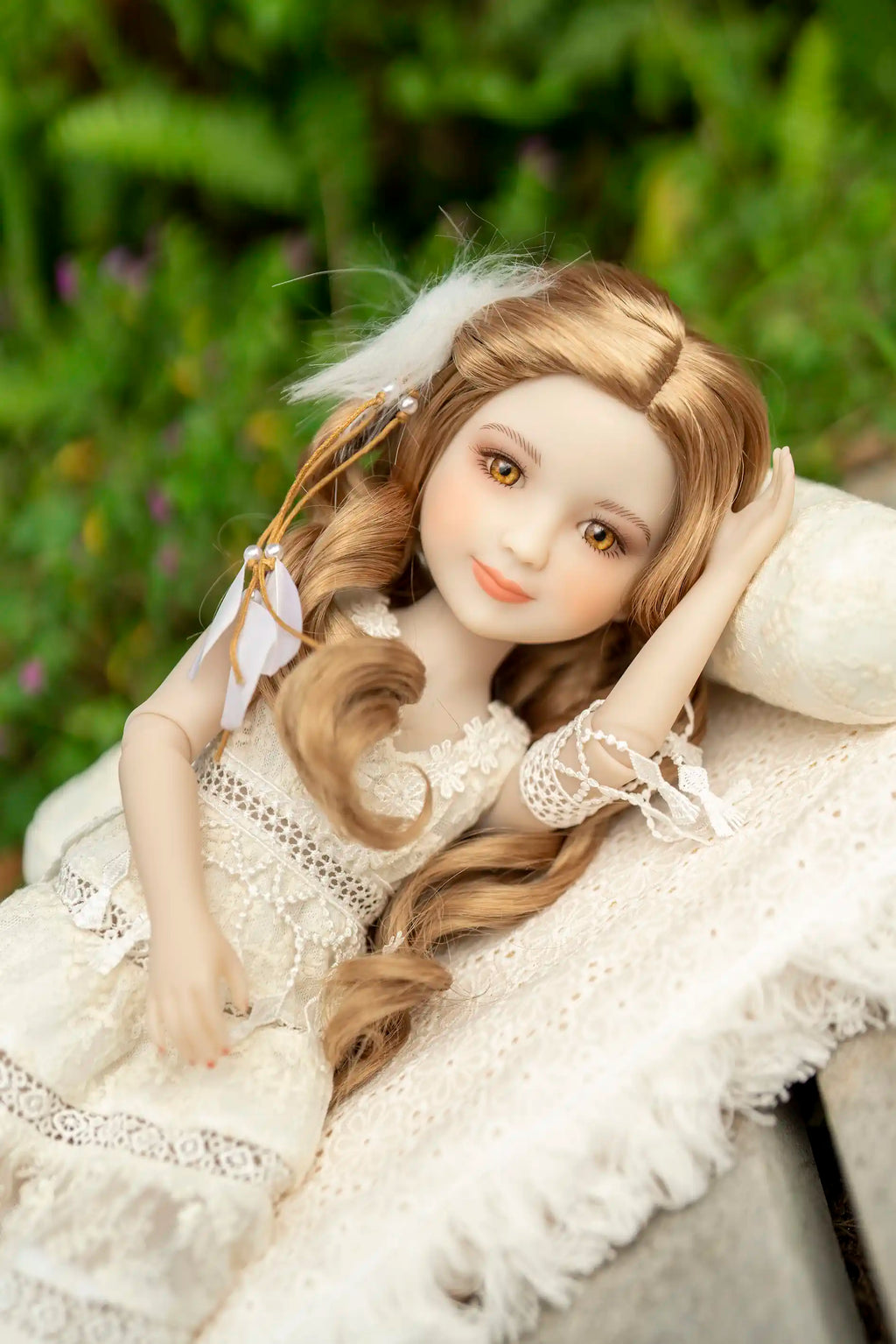 Doll in a white dress with long blonde hair, sitting outdoors.