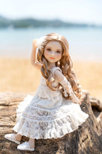 Doll in a white dress sitting on a log by a beach