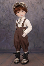 Doll wearing a checkered hat, brown overalls, and black boots against a stone wall background