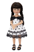 Doll wearing a black and white polka dot dress with lace details on a white background