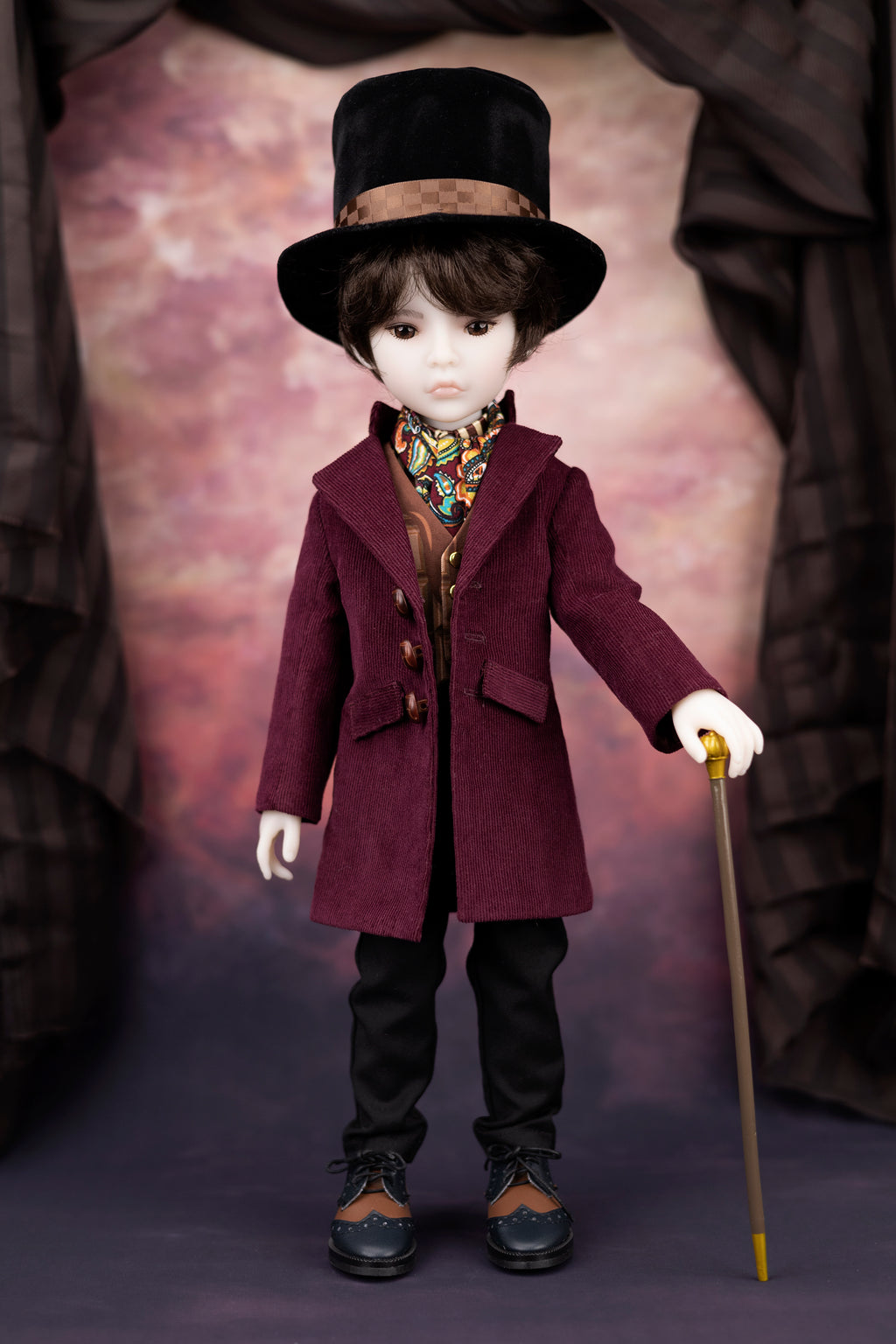Doll in a vintage outfit with a top hat and purple coat against a draped fabric background
