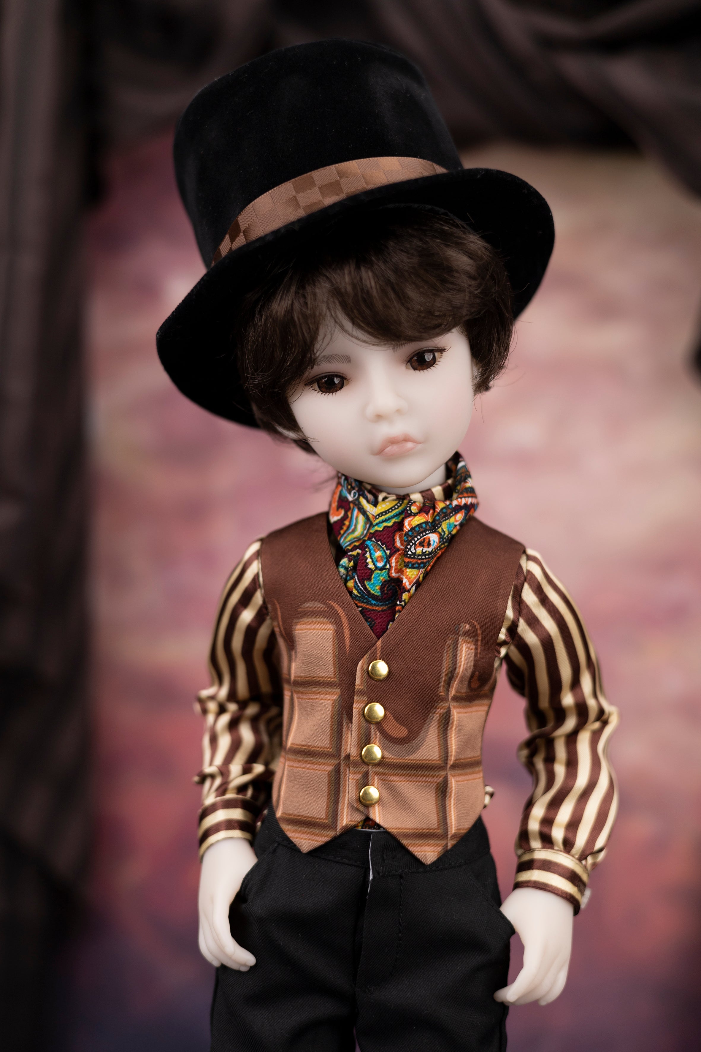 Doll wearing a top hat, striped shirt, vest, and colorful scarf against a blurred background