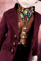 Close-up of a doll wearing aburgundy red corduroy coat and a patterned scarf.