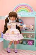 Doll in a pastel outfit standing in front of a 'Sweet Shop' display.