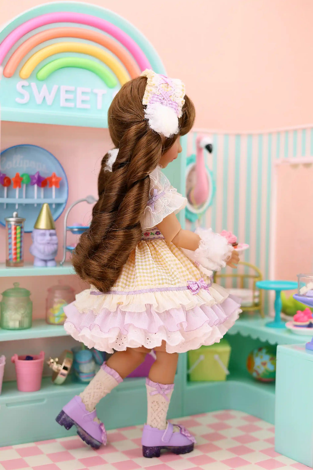 Doll with long hair in a decorative setting with a rainbow and 'Sweet' sign.