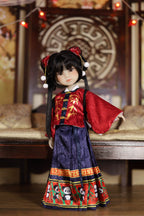 Traditional doll in red and blue outfit with intricate patterns on a wooden bench.
