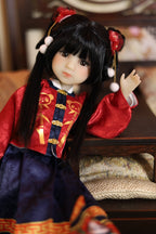 Doll in traditional Chinese red and blue outfit with decorative hair accessories on a wooden surface.