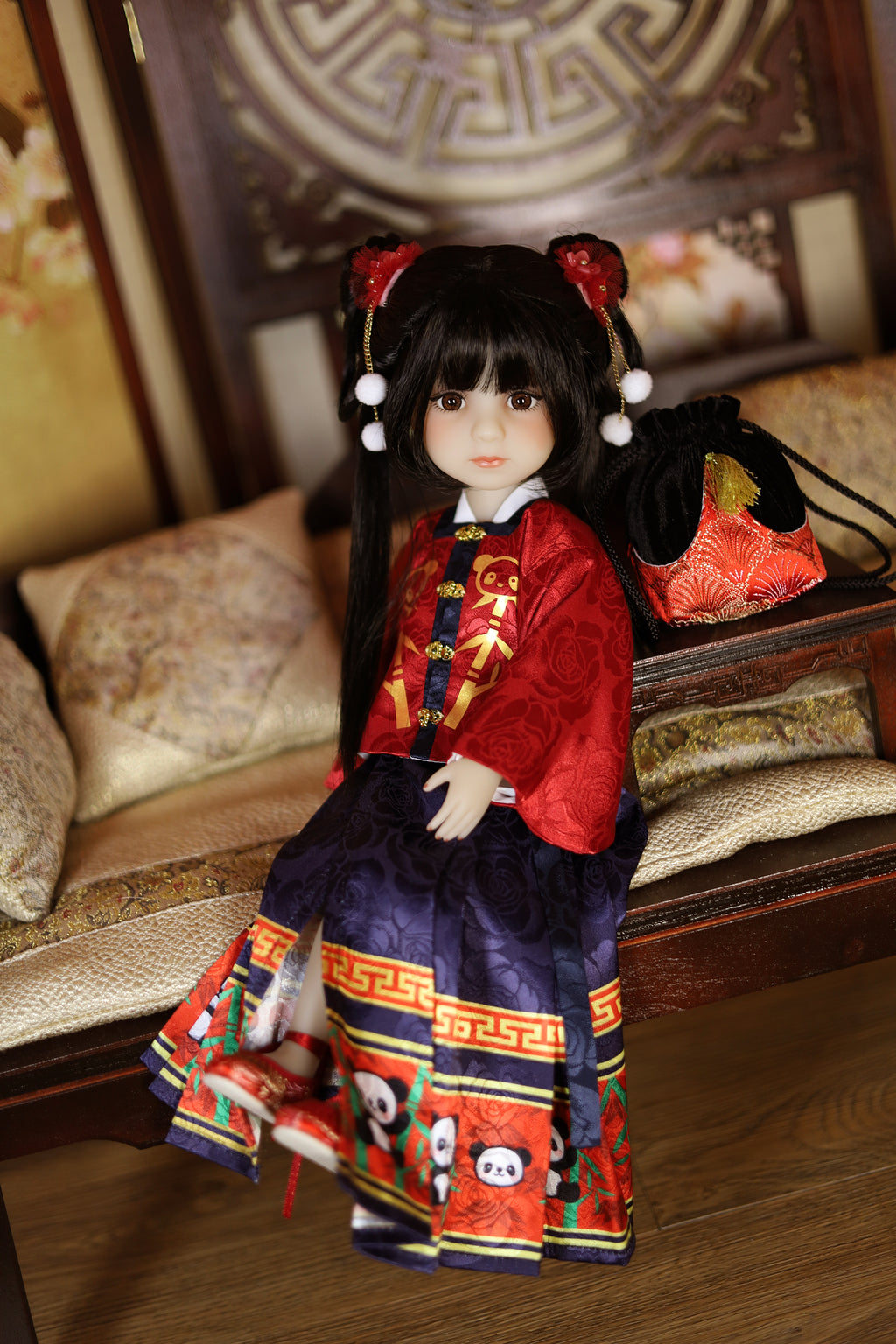 Doll in traditional Chinese outfit sitting on a wooden floor.