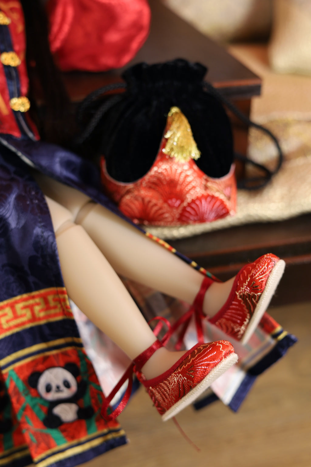 Doll in traditional outfit with red shoes and decorative bag in the background