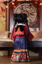 Traditional doll in red and blue outfit with intricate patterns, standing in a decorative setting.