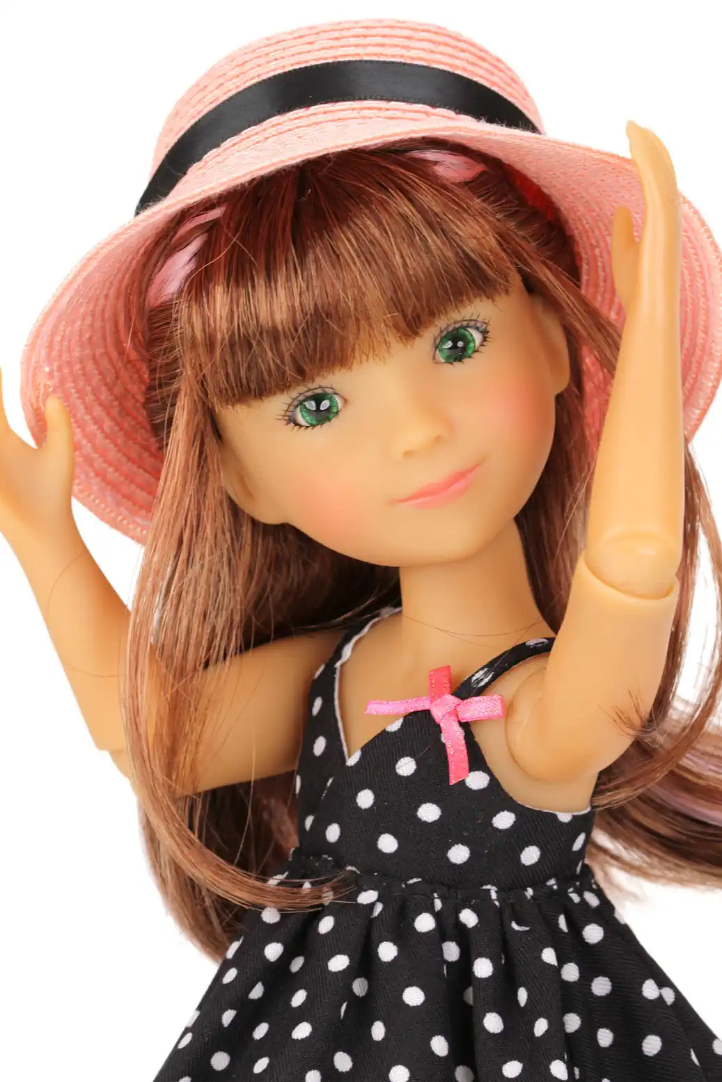 Bailey wearing a pink hat and black polka dot dress on a white background