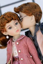 Two dolls with red hair are interacting closely.