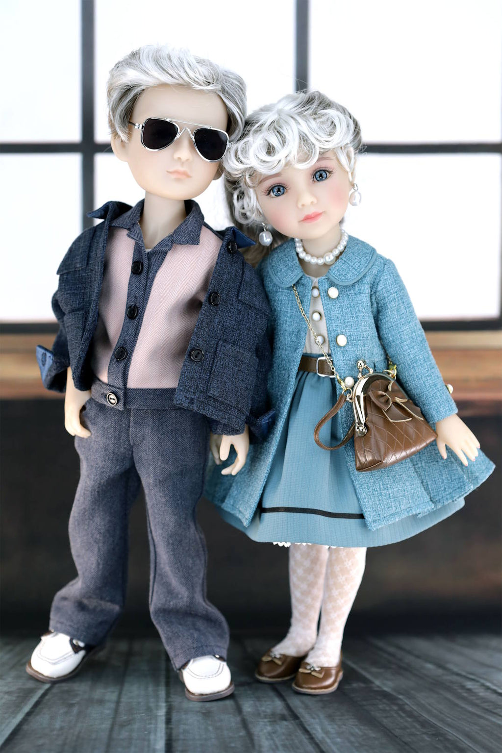 Two dolls dressed in stylish outfits with sunglasses and a handbag.