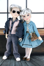 Two dolls dressed in stylish outfits with sunglasses and a handbag.